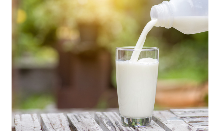 Pouring milk in the glass on the background of nature.