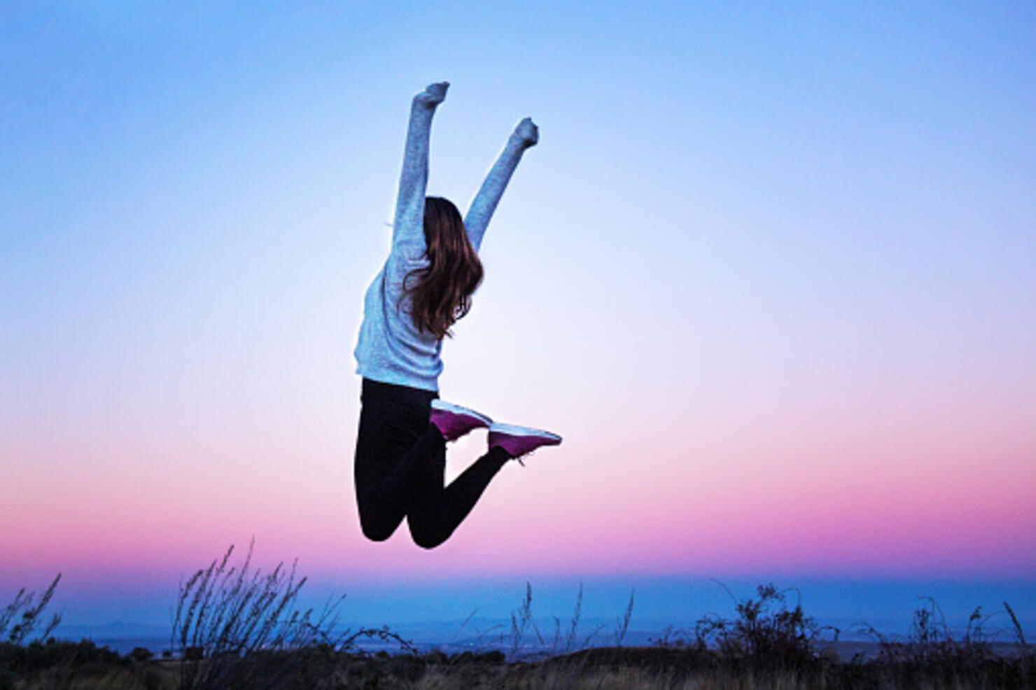 Young woman jumping raising her arms at a colorful sunset - Aragon, Spain