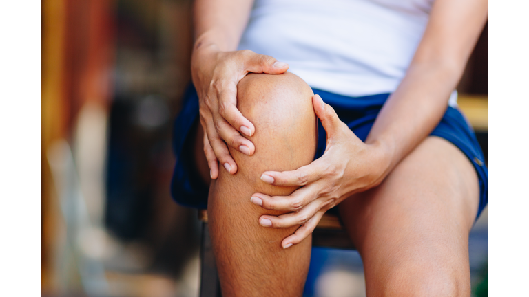 Midsection Of Woman With Knee Pain Sitting On Chair