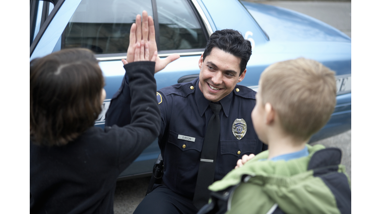 Male police officer high-fiving a young boy