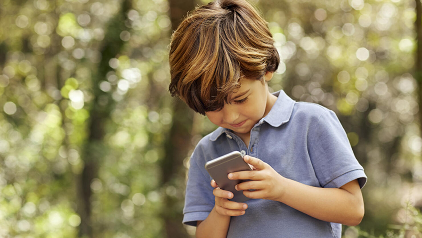 Smiling boy using mobile phone in forest