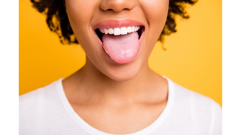 Cropped close up photo beautiful amazing she her dark skin lady beaming whitening toothy smile tongue out perfect mouth wear casual white t-shirt isolated yellow bright vibrant background