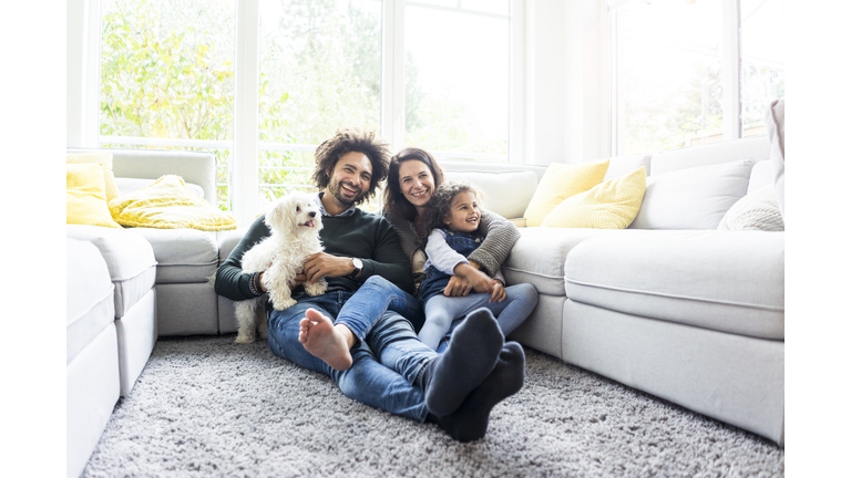 Happy family with dog sitting together in cozy living room