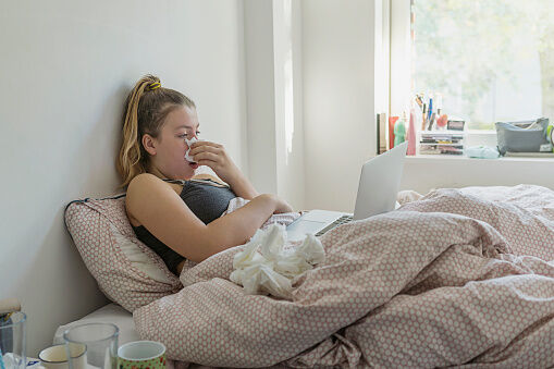 Teenage girl in bed with the flu - Getty Images