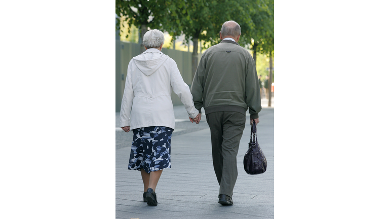 An elderly couple is holding hands while