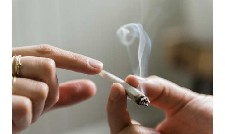 Hands of man and woman passing marijuana joint