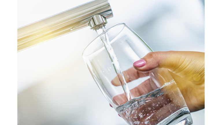 Cropped Hand Of Woman Filling Glass With Water
