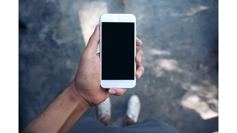 Low Section Of Man Holding Mobile Phone On Street