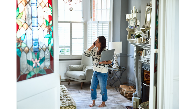 Concerned woman in her 30s on phone with laptop