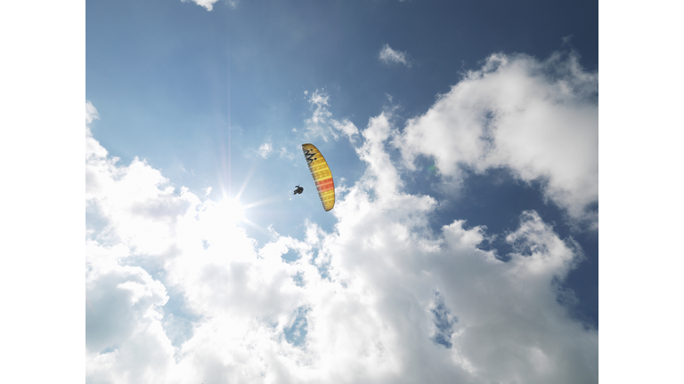 Senior paraglider in midair against sky