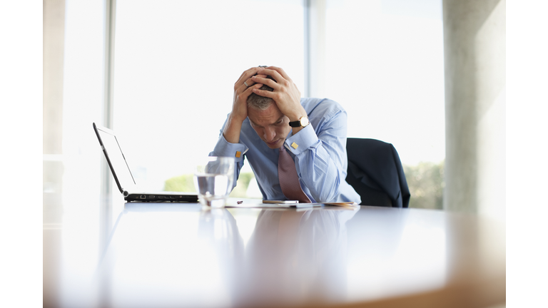 Frustrated businessman with head in hands at desk