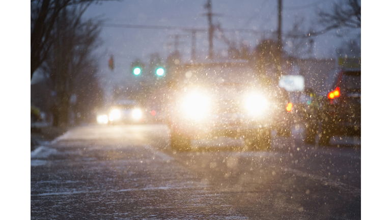 Car driving on snowy urban street at night