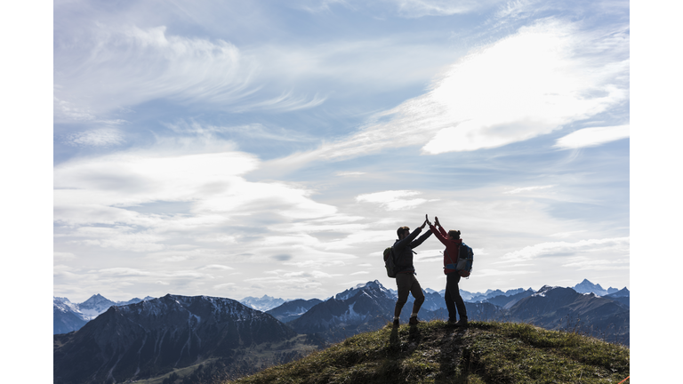 Austria, Tyrol, young couple standing in mountainscape cheering