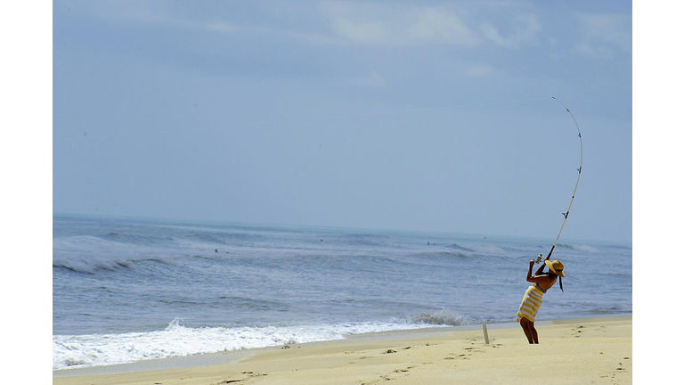 A woman sets a hook  while fishing on th