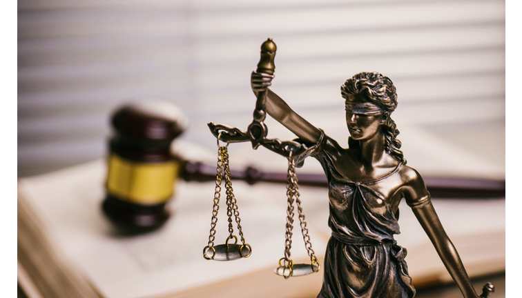 Close Up Of Lady Justice Against Gavel On Book