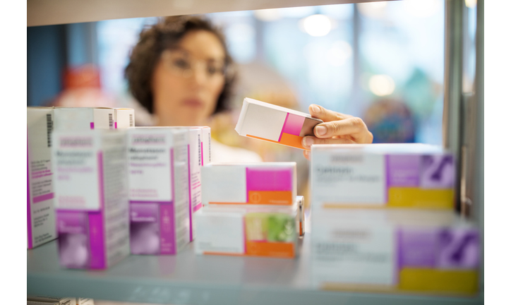 Female pharmacist checking medicines on rack