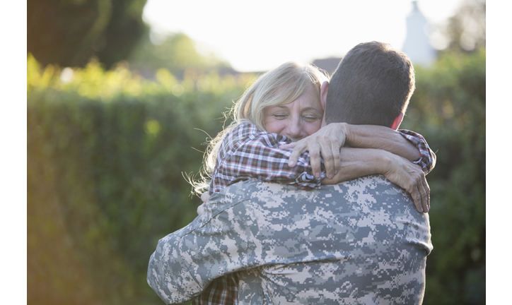 Male soldier hugging mother on street at homecoming
