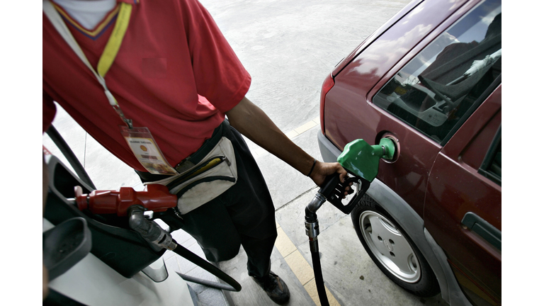 A pump attendant fills up a car with gas