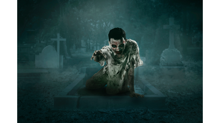 Man Wearing Ghost Costume While Lying At Cemetery