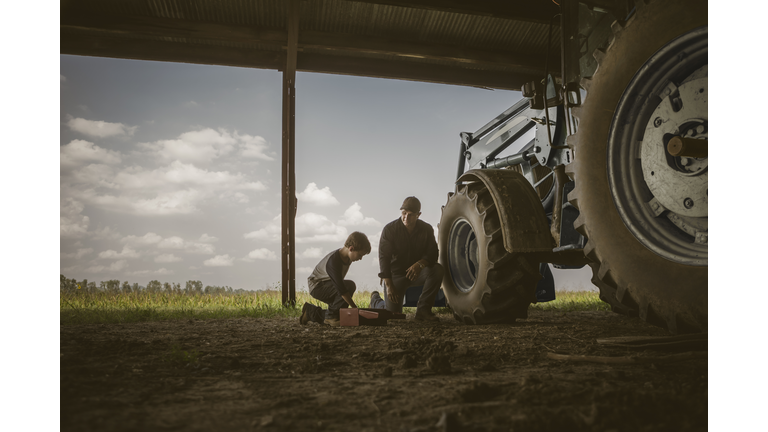 Caucasian father and son working on tractor