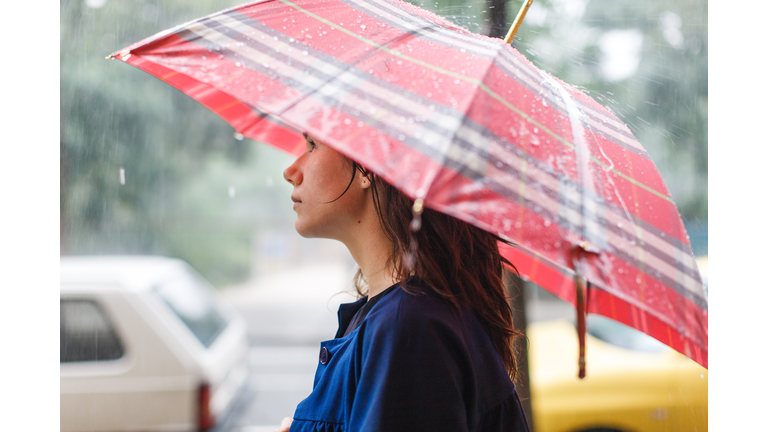 Young woman under umbrella in rain