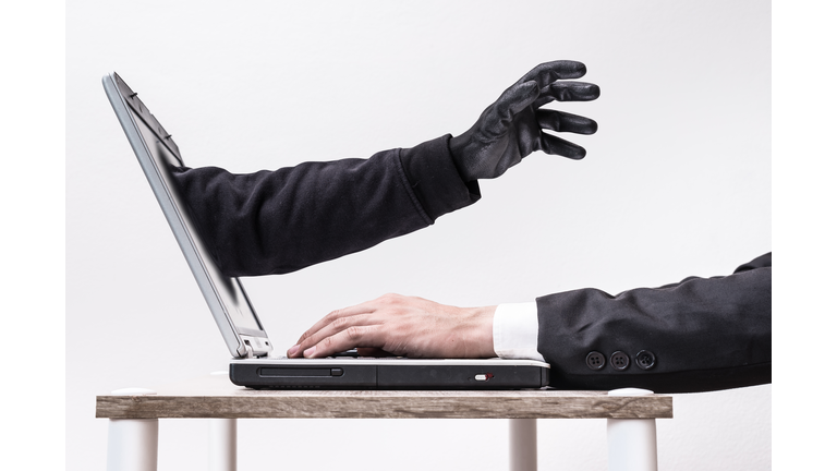 The abstract image of the hacker's hand reach through a laptop screen during business man on typing. the concept of cyber attack, virus, malware, illegally and cyber security.