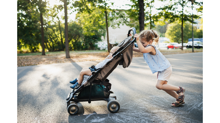 Young Girl Pushing Baby Brother In Stroller