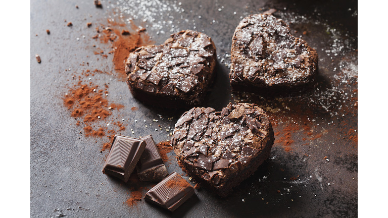 Three heart-shaped brownies and chocolate on metal