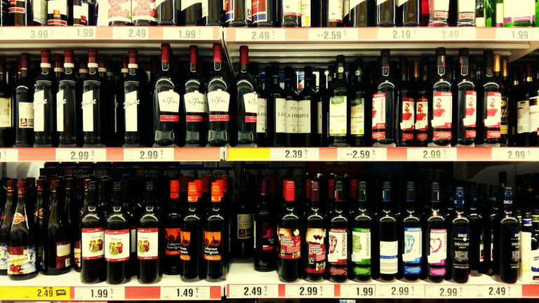 Red Wine Bottles Arranged On Shelves In Store
