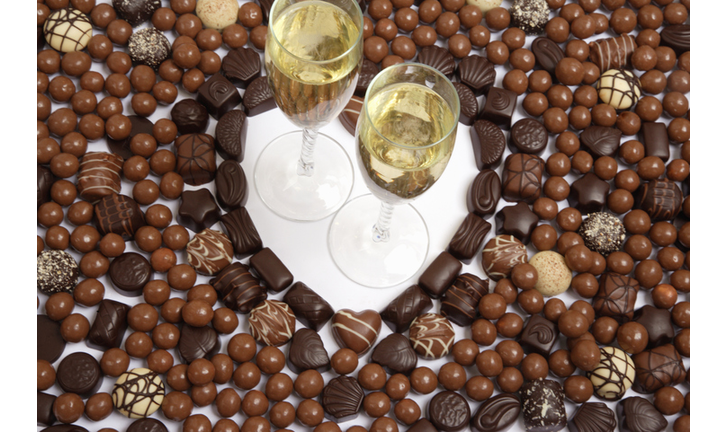 Heart shape created using chocolates with champagne glasses, elevated view, close-up