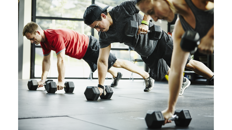 Group of friends doing pushups with dumbbells