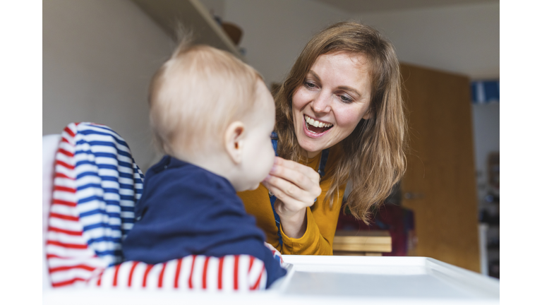 Woman feeding her little son and having fun