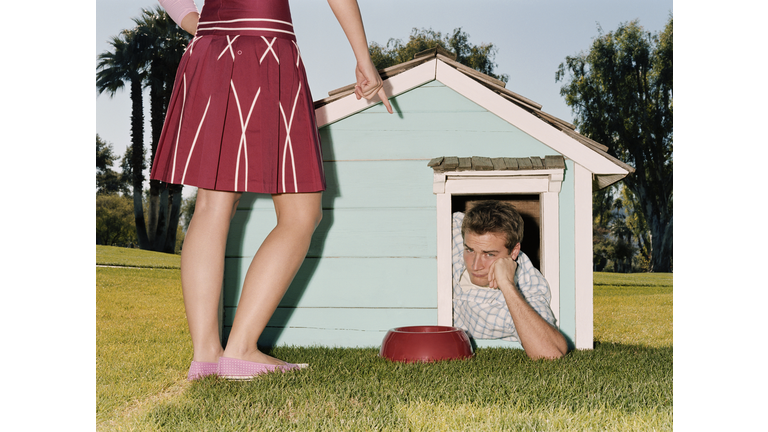 Frustrated man laying in doghouse