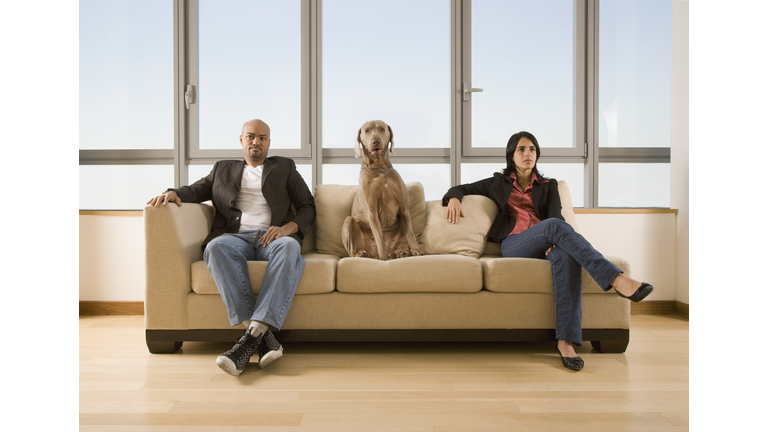 Multi-ethnic couple and dog sitting on sofa