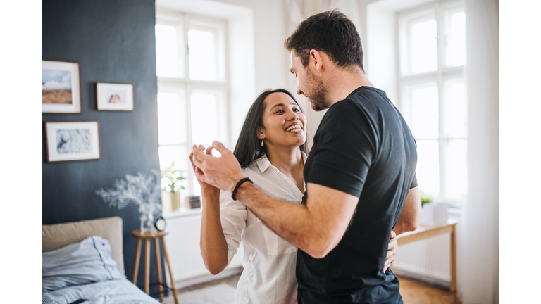 Affectionate young couple in love dancing at home, having fun.