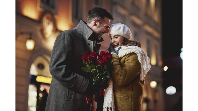 Man giving his amazed girlfriend bunch of red roses on Valentine's Day