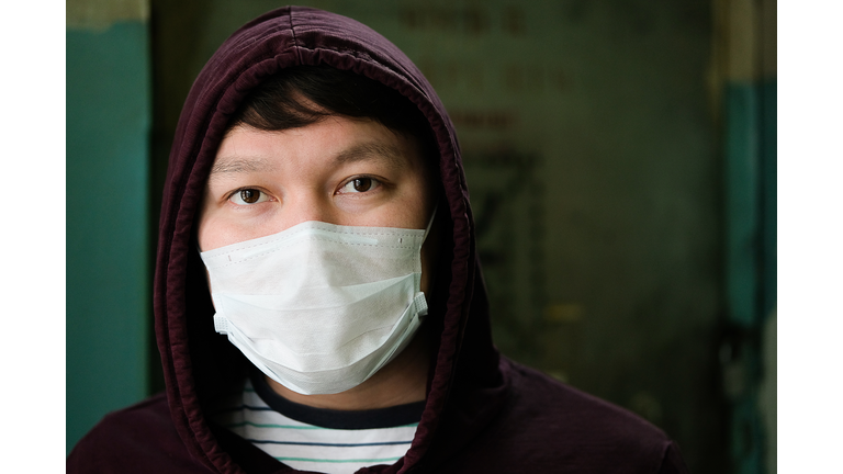 An Asian or Chinese man Wearing a Hood and Medical Mask is Protected from the Coronavirus. The Concept Of Air Pollution, Pneumonia Outbreaks, Epidemics, And The Biological Danger Of Viral Infection.