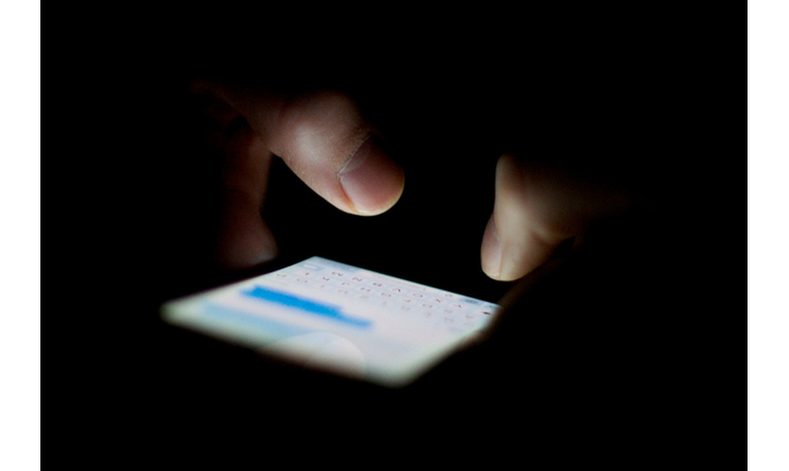 Cropped Hands Typing On Mobile Phone In Dark