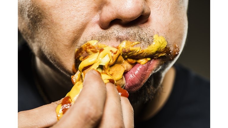 Mid adult man eating a hot dog,close up shot