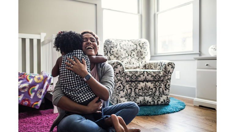 Mother and daughter playing on bedroom floor