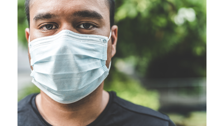 Close-Up Portrait Of Man Wearing Pollution Mask While Standing Against Trees