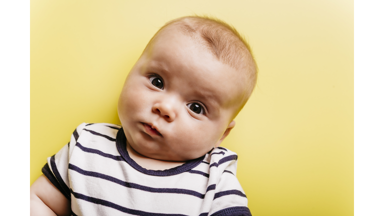 Portrait of sceptical baby girl in front of yellow background