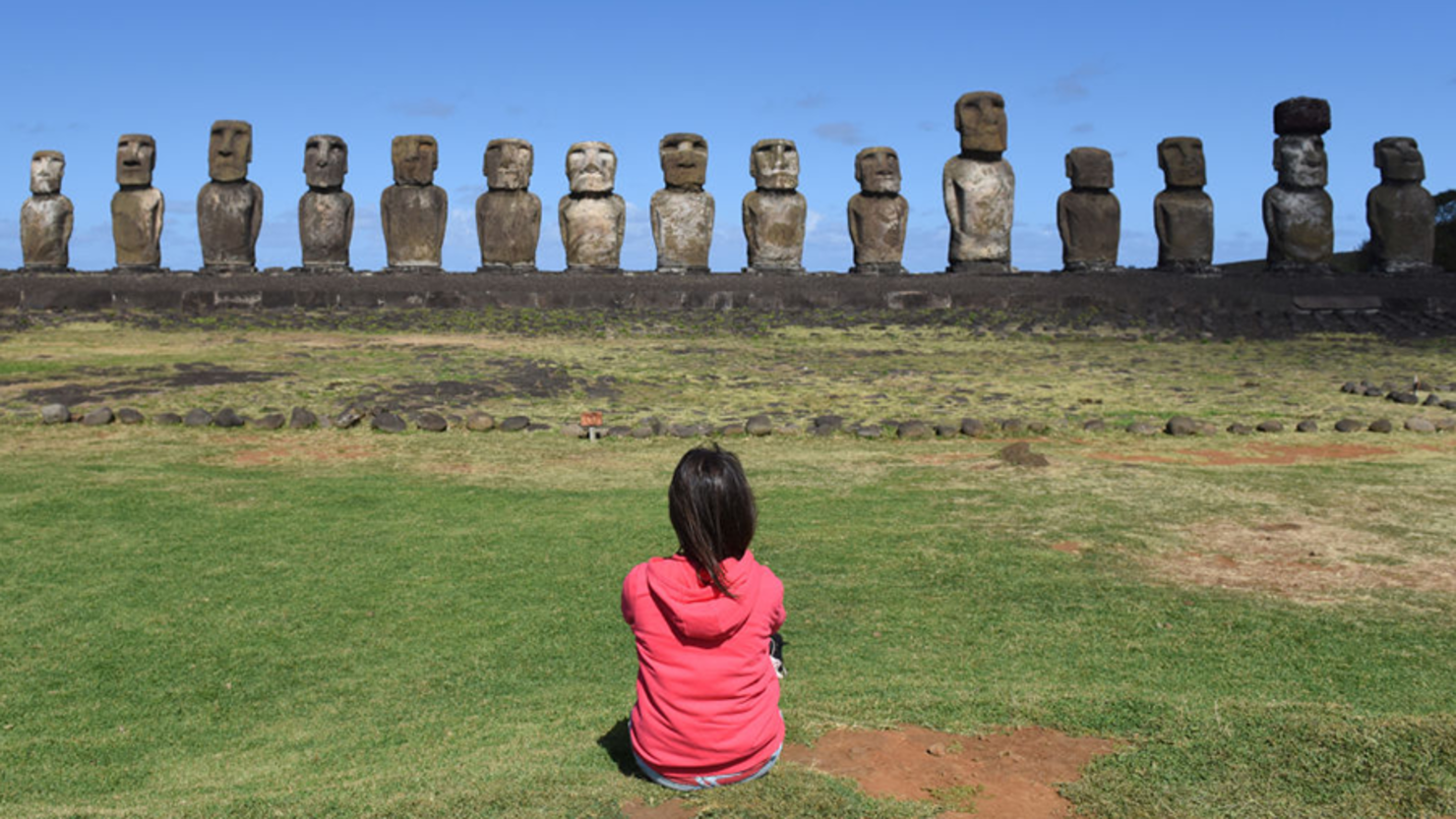 A woman gazes at Moais on ceremonial platform Ahu Tongariki.