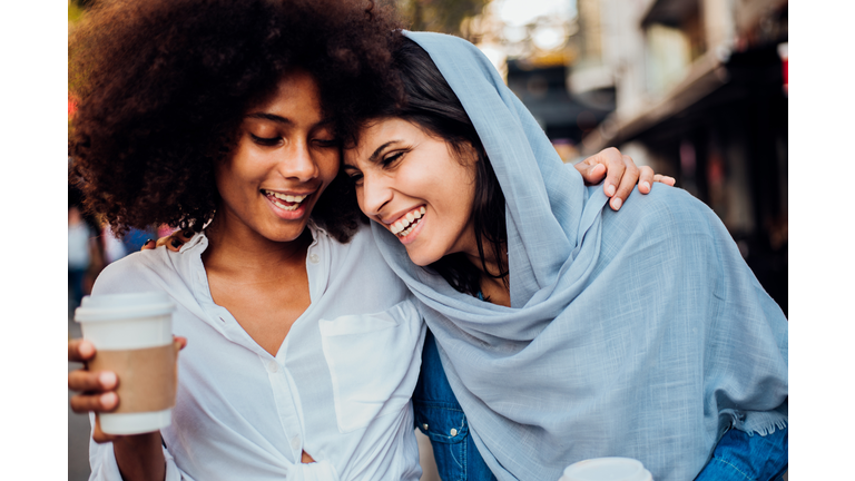 Portrait of the Afro girl and her Arab friend drinking coffee