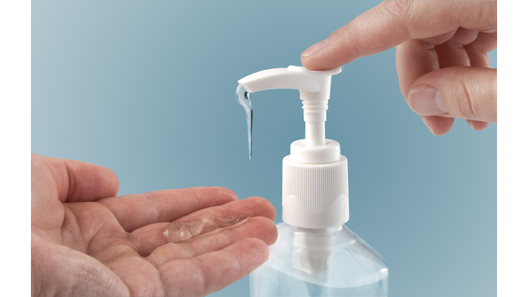 Photograph of a finger pumping sanitizer onto hand