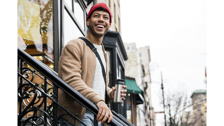 Smiling young man walking down stairs in city