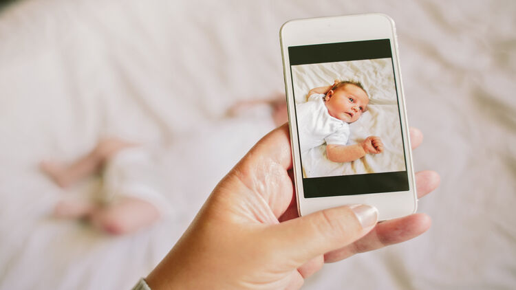 Mother taking a smartphone picture of her baby