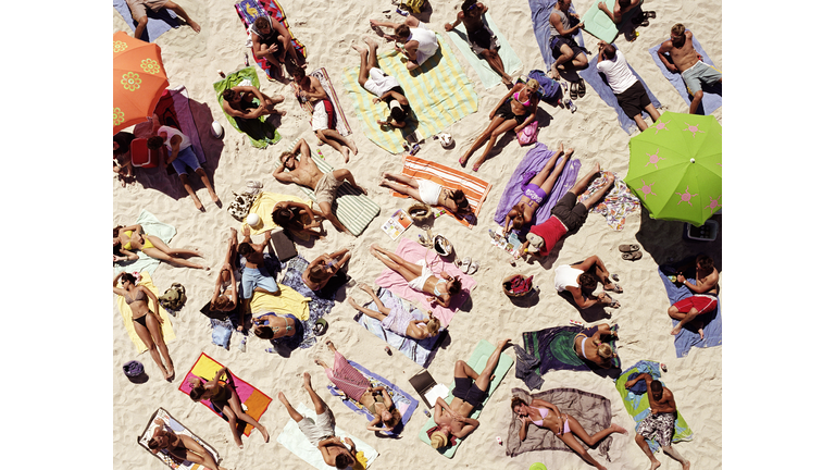 Crowd of people sunbathing on beach, over head view