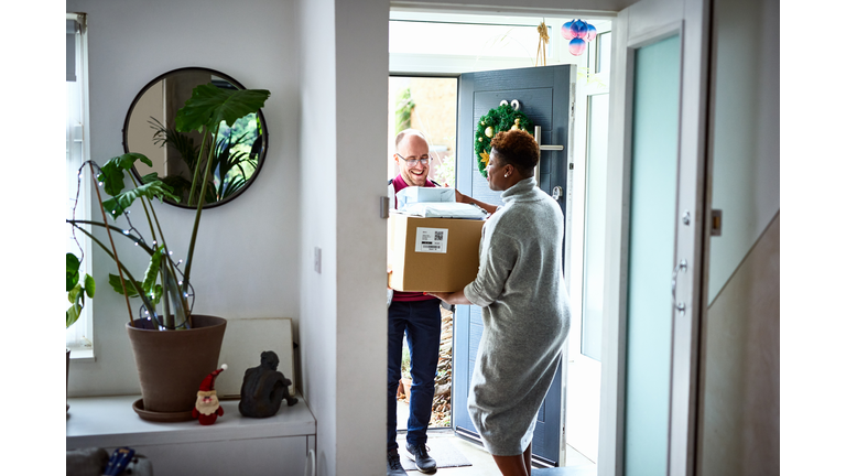 Delivery man handing over cardboard box to female customer