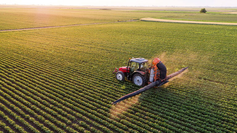 Serbia, Vojvodina, Aerial view of a tractor spraying soybean crops